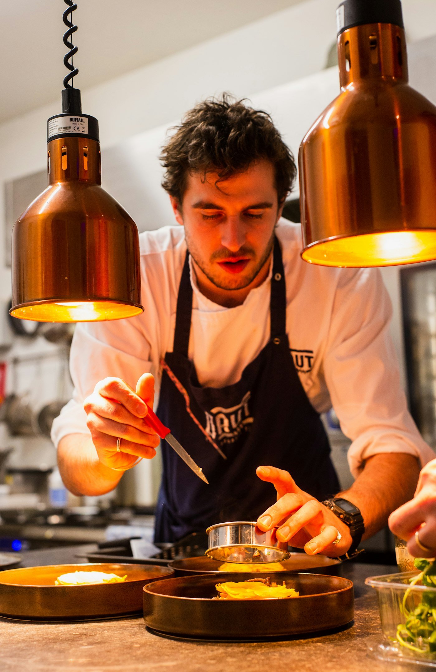 Head chef garnishing a gourmet plated dish in the kitchen